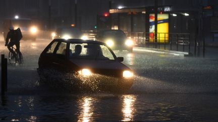 Un cycliste et un automobiliste sur une route inondée, le 4 juin 2018 au Mans en Mayenne.&nbsp; (JEAN-FRANCOIS MONIER / AFP)