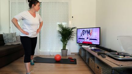 Une femme faisant du sport dans son salon pendant le confinement, le 17 mars 2020 à Lastrene (Gironde). Photo d'illustration. (LAURENT THEILLET / MAXPPP)