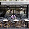 Un serveur nettoie les tables de la terrasse de son café en prévision de la levée des restrictions liées au Covid-19, mardi 11 mai 2021 à Paris. (LUDOVIC MARIN / AFP)