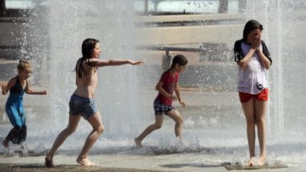 Des enfants sous l'eau d'une fontaine, à Lyon, où il fait 32°, le 19 août 2011 (AFP/PHILIPPE DESMAZES)