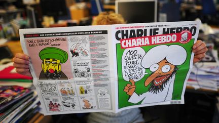 Une personne lit un num&eacute;ro du journal satirique fran&ccedil;ais "Charlie Hebdo", le 1er novembre 2011.&nbsp; (MARTIN BUREAU / AFP)