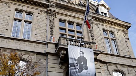 Une photo de Samuel Paty déroulée sur la façade de l'hôtel de ville de Conflans-Saint-Honorine (Yvelines) où il enseignait, le 3 novembre 2020. (Thomas COEX / AFP)