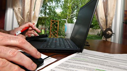 Un homme utilise un ordinateur depuis chez lui. (ERIC MALOT / MAXPPP)