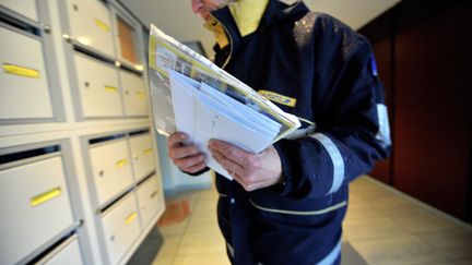 Un facteur dépôse le courrier dans des boîtes aux lettres, le 24 novembre 2008, à Caen (Calvados). (MYCHELE DANIAU / AFP)