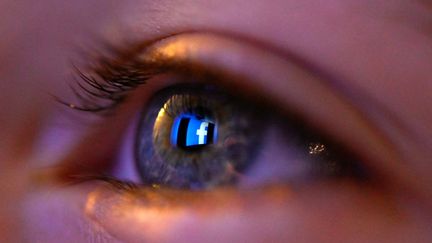 Le logo de Facebook se reflète dans l'œil d'une femme à Rennes (Ille-et-Vilaine), le 12 janvier 2020. (DAMIEN MEYER / AFP)