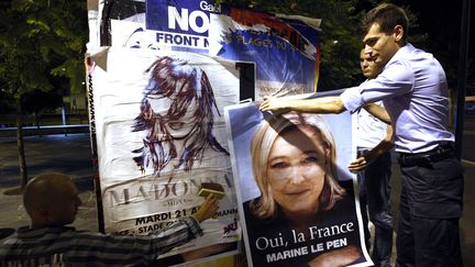 Des militants du FN recouvrent les affiches annon&ccedil;ant le concert de Madonna par des affiches de Marine Le Pen, le 18 ao&ucirc;t 2012 &agrave; Nice (Alpes-Maritimes). (ERIC GAILLARD / REUTERS)