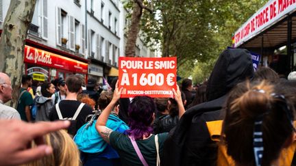 Des manifestants brandissent une pancarte réclamant l'augmentation du smic à 1 600 euros, le 7 septembre 2024. (FLORE GASTAL / HANS LUCAS / AFP)