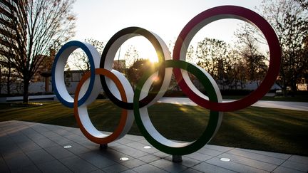 Les anneaux olympiques devant le Japan National Stadium. Les Jeux olympiques de Tokyo 2020 sont repoussés d'un an à cause de la pandémie de coronavirus.&nbsp; (BEHROUZ MEHRI / AFP)