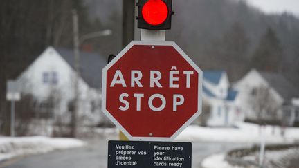 Un panneau d'arrêt bilingue à la frontière entre les États-Unis et le Canada, à East Hereford au Québec en 2017. Photo d'illustration. (DON EMMERT / AFP)