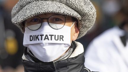 Une manifestante portant un masque sur lequel est inscrit le mot "Diktatur" ("dictature"), lors d'une manifestation à Francfort (Allemagne), le 14 novembre 2020. (BORIS ROESSLER / DPA / AFP)