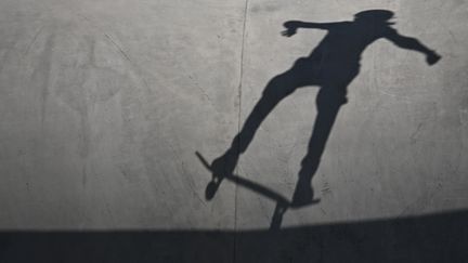 La skateuse qui ride plus vite que son ombre. La preuve, elle est hors champ alors que son ombre y est encore. (LIONEL BONAVENTURE / AFP)