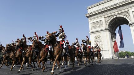 Des cavaliers de la Garde r&eacute;publicaine devant l'Arc de triomphe, &agrave; Paris, le 14 juillet 2013. (ETIENNE LAURENT / AFP)