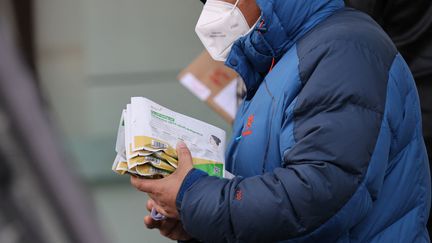 Un homme sort d'une pharmacie avec des tests antigéniques, à Xian, dans le centre de la Chine, le 20 décembre 2022. (STR / AFP)