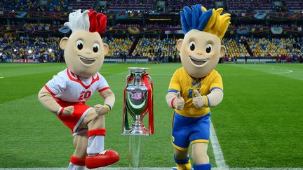 Slavek et Slavko, les mascottes de l'Euro, entourent le troph&eacute;e avant la finale Espagne-Italie. (FRANCK FIFE / AFP)