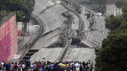 Des badauds assistent &agrave; la destruction d'un tron&ccedil;on d'une autoroute &agrave; Rio de Janeiro (Br&eacute;sil), le 20 avril 2014. (RICARDO MORAES / REUTERS)