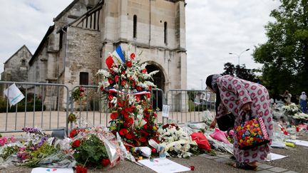 Une femme dépose des fleurs devant l'église de Saint-Etienne-du-Rouvray (Seine-Maritime), où le prêtre Jacques Hamel a été assassiné, le 29 juillet 2016. (CHARLY TRIBALLEAU / AFP)