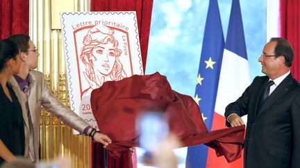 Le président François Hollande et des lycéens dévoilent le nouveau timbre Marianne à l'Elysée le 14 juillet 2013
 (François Mori / AFP)