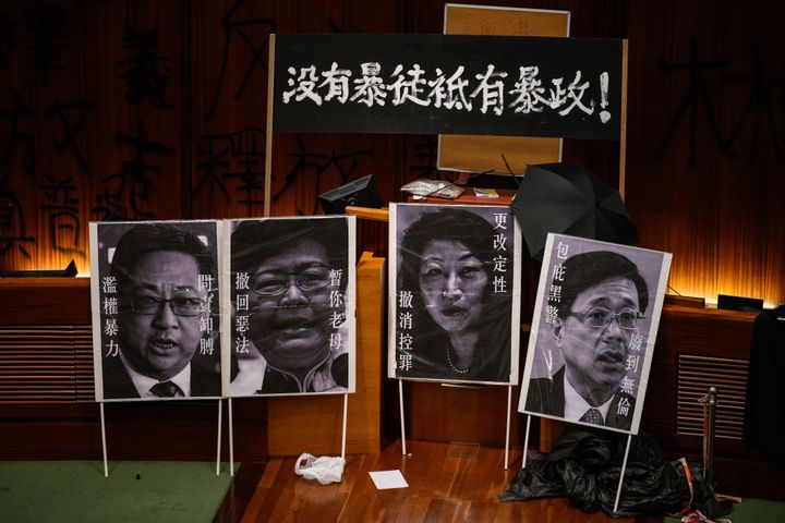 Des portraits de différents ministres hongkongais, dont la cheffe du gouvernement Carrie Lam (deuxième portrait sur la gauche), déployés par des manifestants dans l'hémicycle du parlement, lundi 1er juillet 2019. (ANTHONY WALLACE / AFP)