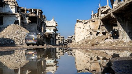 Un véhicule passe le long d'une rue à côté de bâtiments détruits dans la zone dévastée de Hajar Aswad, dans la banlieue sud de Damas, le 1er janvier 2025. (MUHAMMAD HAJ KADOUR / AFP)