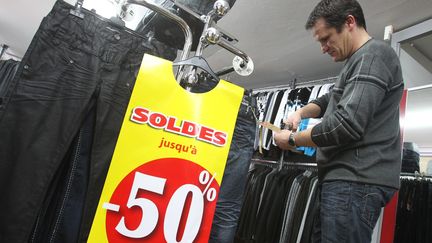 Un homme pr&eacute;pare les soldes d'hiver dans un magasin de v&ecirc;tements &agrave; Hirson (Aisne), le 10 janvier 2012. (FRED HASLIN / LE COURRIER PICARD / MAXPPP)