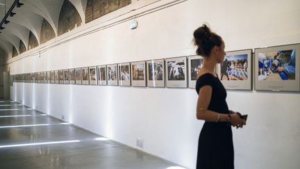 Une membre de l'équipe de Visa pour l'image observe des photos de Loay Ayyoub, réunies pour l'exposition "La tragédie de Gaza", le 28 août 2024 à Perpignan. (IDRISS BIGOU-GILLES / AFP)