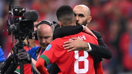 Le sélectionneur marocain Walid Regragui console son joueur Azzedine Ounahi après la défaite en demi-finale de la Coupe du monde face à la France, au stade Al-Bayt de Doha (Qatar), le 14 décembre 2022. (KIRILL KUDRYAVTSEV / AFP)