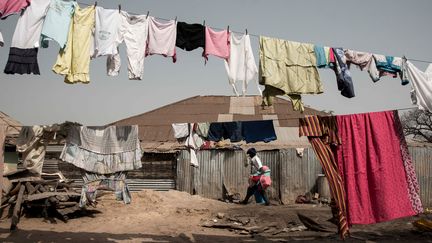 Dans un bidonville de Bissau, un homme transporte des marchandises pour les vendre sur le marché. (XAUME OLLEROS / AFP)