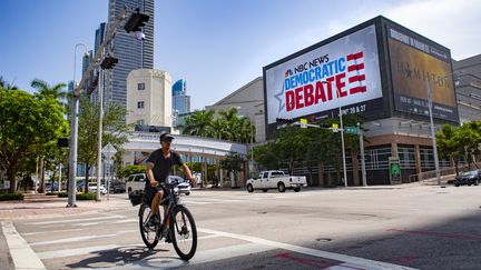 Un homme passe en vélo devant le&nbsp;Adrienne Arsht Center for Performing Arts, le 25 juin 2019, à Miami, où se tiendra le premier débat. (JIM WATSON / AFP)