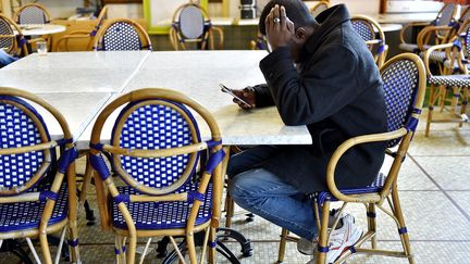 Un homme venu du Soudan consulte son téléphone portable dans un centre d'accueil et d'orientation pour migrants, à Saint-Brévin-les-Pins (Loire-Atlantique), le 4 janvier 2017. (LOIC VENANCE / AFP)