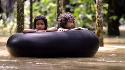 Des enfants thaïlandais sur une chambre à air flottant sur les eaux, dans la province de Narathiwat, le 2 novembre 2010 (AFP PHOTO / MADAREE TOHLALA)