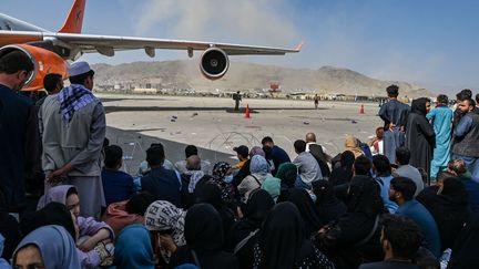 Des Afghans attendent à l'aéroport de Kaboul, 16 août 2021. (WAKIL KOHSAR / AFP)