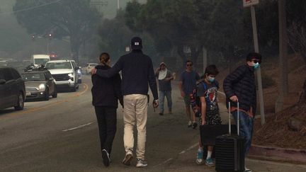 Des Californiens évacuent le long du Sunset Boulevard, le 7 janvier 2025. Près de 30 000 personnes sont sous le coup d'un ordre d'évacuation mercredi 8 janvier, selon les autorités. Deux décès civils et "de nombreux blessés graves" ont été signalés. (APU GOMES / GETTY IMAGES NORTH AMERICA / AFP)