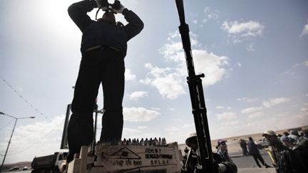 Un rebelle libyen scrute le ciel de Ras Lanouf où les bombardements ont repris, le 9 mars 2011. (AFP PHOTO / MARCO LONGARI)