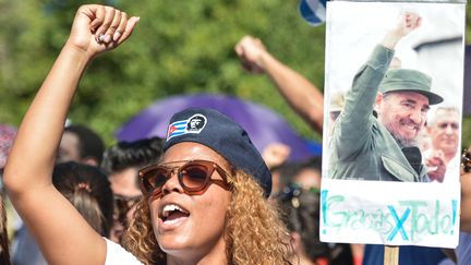 Une Cubaine lève le poing à côté d'une pancarte avec une affiche de Fidel Castro, lundi 28 novembre 2016 à La Havane (Cuba). (ARTUR WIDAK / NURPHOTO / AFP)