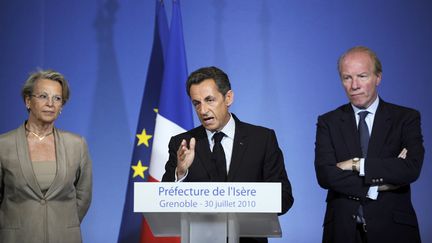 Le pr&eacute;sident de la R&eacute;publique de l'&eacute;poque, Nicolas Sarkozy, avec Mich&egrave;le Alliot-Marie, alors garde des Sceaux, et le ministre de l'Int&eacute;rieur,&nbsp;Brice Hortefeux, le 30 juillet 2010 &agrave; la pr&eacute;fecture de l'Is&egrave;re, &agrave; Grenoble. (PHILIPPE DESMAZES / AFP)