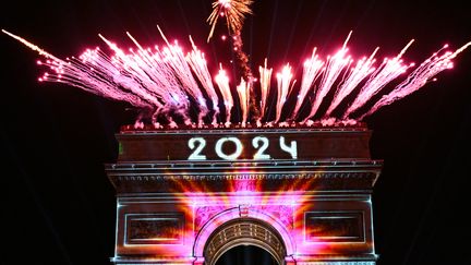 L'Arc de Triomphe éclairé et les feux d'artifice tirés pour la nouvelle année, à Paris, le 1er janvier 2024. (BERTRAND GUAY / AFP)