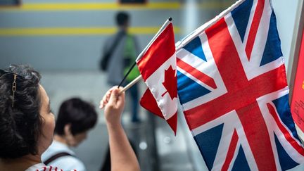 Une femme brandit des drapeaux britannique et canadien sur un escalator du métro après les célébrations du couronnement de l'Ontario, le 6 mai 2023 à Queen's Park à Toronto, au Canada. (KATHERINE KY CHENG / GETTY IMAGES NORTH AMERICA)