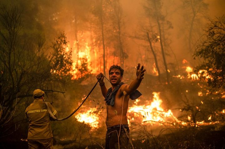 Des Grecs luttent contre un feu de forêt, le 8 août 2021 à Pefki. (ANGELOS TZORTZINIS / AFP)