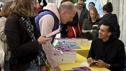 Gaël Faye en séance de dédicaces à Nancy pour la sortie de "Jacaranda" son nouveau roman, publié chez Grasset, lors de la 46e édition du "Livre sur la place", premier salon du livre de la rentrée, le 14 septembre 2024. (ALEXANDRE MARCHI / MAXPPP)