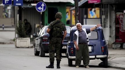 Un homme discute avec un policier, &agrave; Kumanovo (Mac&eacute;doine), le 10 mai 2015, alors que des heurts ont oppos&eacute; les forces de l'ordre &agrave; un groupe arm&eacute;.&nbsp; (OGNEN TEOFILOVSKI / REUTERS)