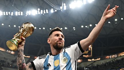 Lionnel Messi,&nbsp;capitaine de l'équipe d'Argentine, soulève&nbsp;la Coupe du monde après la victoire contre l'équipe de France, le 18 décembre 2022. (ANNE-CHRISTINE POUJOULAT / AFP)