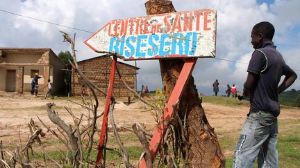 Un jeune homme se tient à côté d'un panneau indiquant un centre de santé à Bisesero, dans l'ouest du Rwanda, le 2 décembre&nbsp;2015. (STEPHANIE AGLIETTI / AFP)