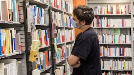 Un jeune homme regarde les livres dans les rayons d'une librairie à Lorient le 21 août 2020. (MAUD DUPUY / HANS LUCAS)