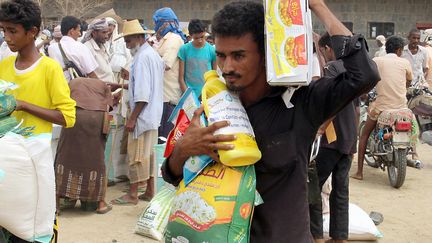 Des Yéménites, déplacés à cause du conflit, reçoivent une aide alimentaire de la part d'une ONG japonaise, à Abs, le 15 août 2018. (ESSA AHMED / AFP)