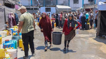 Displaced Palestinians during a water distribution organized by UNRWA at the Jabalia refugee camp, northern Gaza Strip, on July 23, 2024. (OMAR AL-QATTAA / AFP)