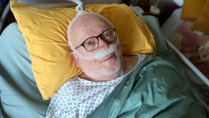 Philippe Bail pose dans son lit médicalisé, chez lui, à Ploubezre (Côtes-d'Armor), le 30 novembre 2023. (YANN THOMPSON / FRANCEINFO)