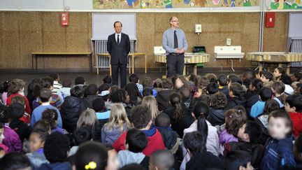 Le candidat socialiste &agrave; l'&eacute;lection pr&eacute;sidentielle, Fran&ccedil;ois Hollande observe une minute de silence avec les enfants de l'&eacute;cole Jean Jaur&egrave;s en hommage aux victimes de la tuerie de Toulouse, Le Pr&eacute;-Saint-Gervais, le 20 mars 2012. (PHILIPPE WOJAZER / AFP)