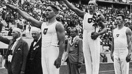 ce qui permet à Hitler de les utiliser pour sa propagande. Les Jeunesses hitlériennes ouvrent la cérémonie au Stade olympique de Berlin sur une musique de Wagner. L’événement commence alors devant 100.000 spectateurs. Ces Jeux sont les premiers à être diffusés à Berlin sur des écrans. En 1938, la cinéaste Leni Riefenstahl en tirera un film, «Olympia» (Titre français : «Les Dieux du stade»).  (AFP/HO/CORR)