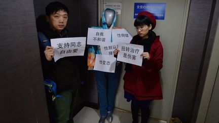 Deux militants LGBT conduisent un mannequin (c) dans une clinique proposant une "r&eacute;orientation sexuelle", le 10 d&eacute;cembre 2013, &agrave; P&eacute;kin (Chine). (MARK RALSTON / AFP)