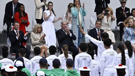 Après avoir sillonné la France depuis trois mois, la flamme olympique fait une arrivée très remarquée à Paris, et s'arrête devant la tribune présidentielle au défilé du 14-Juillet. (JULIEN DE ROSA / AFP)